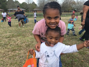 Eight-year-old Aujanae Blakeney of the Forrest Road community helps her cousin, 2-year-old Karmello Taylor, search for eggs during Thursday’s Wilson Housing Authority Easter egg hunt. More than 800 eggs were scattered across the field behind the Forrest Road Community Center and Aujanae and Karmello were among the more than 50 kids who searched for them.